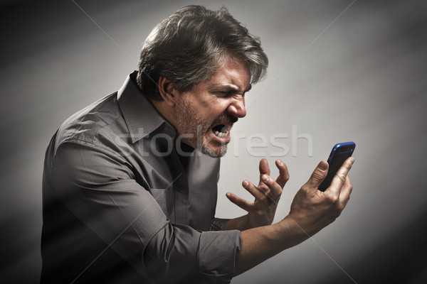 Angry screaming man with cell phone. Stock photo © Kurhan
