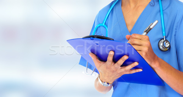 Stock photo: Doctor hands writing on a clipboard.