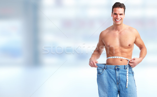 Man measuring waist size over blue background. Stock photo © Kurhan