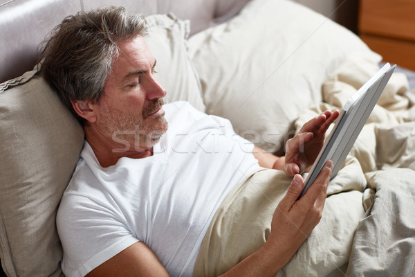 Adam yakışıklı adam rahatlatıcı e-kitap yatak Stok fotoğraf © Kurhan