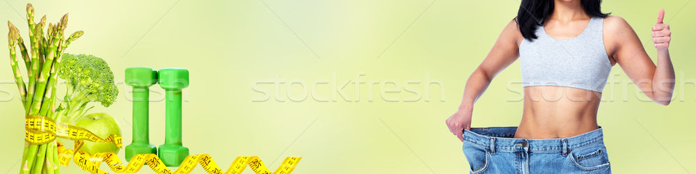Slimming woman wearing big pants over green background. Stock photo © Kurhan