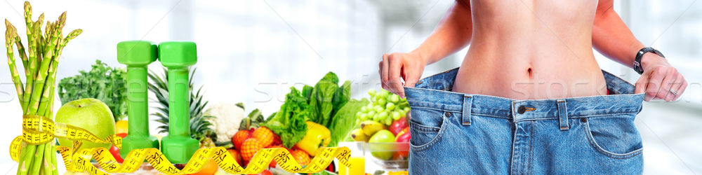 Slimming woman wearing big pants over blue background. Stock photo © Kurhan