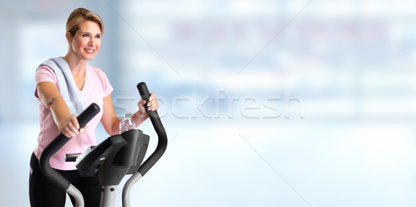 Mature woman doing exercise on elliptical trainer. Stock photo © Kurhan