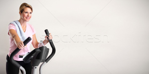 Mature woman doing exercise on elliptical trainer. Stock photo © Kurhan