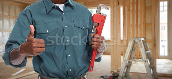Stock photo: Plumber hands with a pipe wrench .
