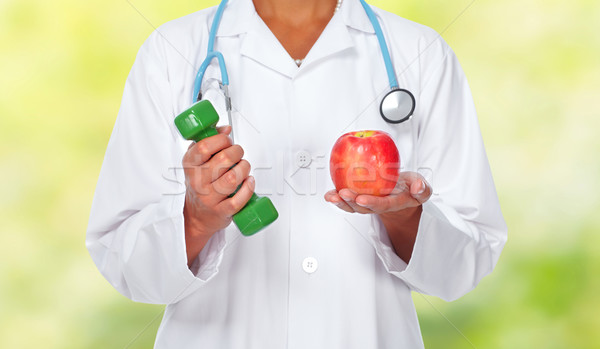 Stock photo: Doctor woman hands with dumbbell and apple.