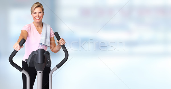Mature woman doing exercise on elliptical trainer. Stock photo © Kurhan