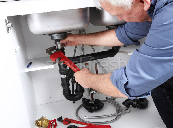 Stock photo: Hands of Plumber with a wrench.