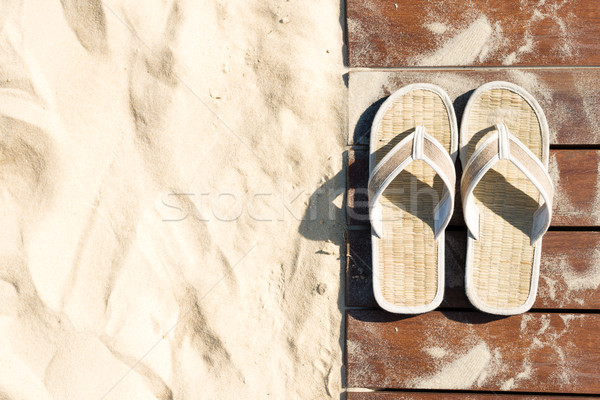 Sand and flip flops on boardwalk at sunny beach. Stock photo © kyolshin