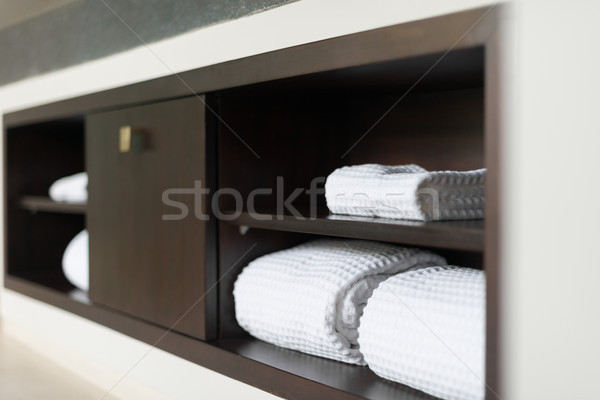Stock photo: Rolled white towels on shelf in hotel bathroom.