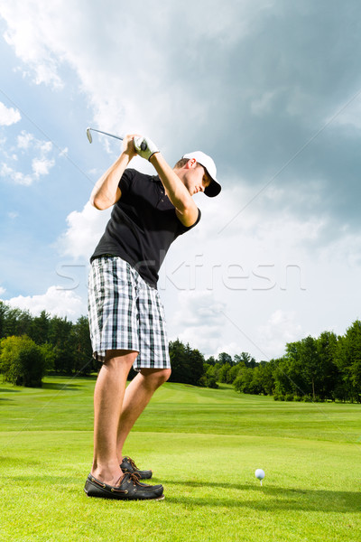 Young golf player on course doing golf swing Stock photo © Kzenon