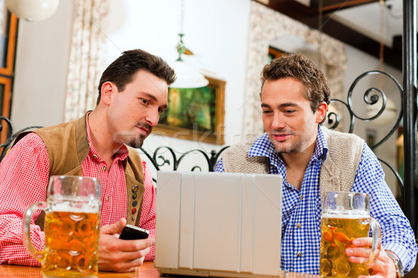 Doua prietenii pub laptop traditional haine Imagine de stoc © Kzenon