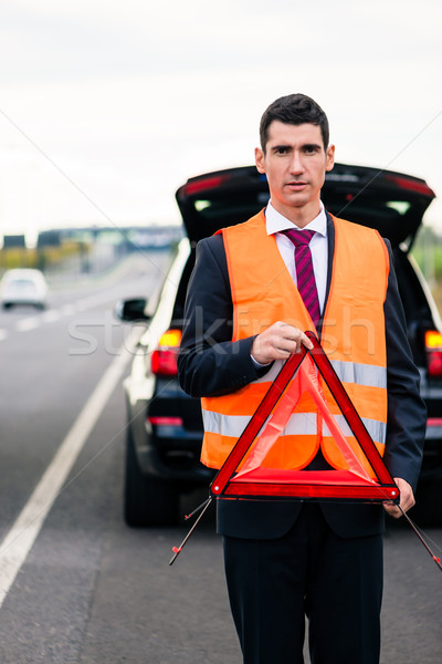 Man with car breakdown erecting warning triangle Stock photo © Kzenon