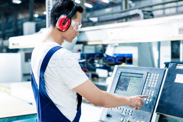 Stock photo: Worker entering data in CNC machine at factory