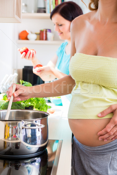Femeie gravida gătit cel mai bun prieten oală aragaz alimente Imagine de stoc © Kzenon