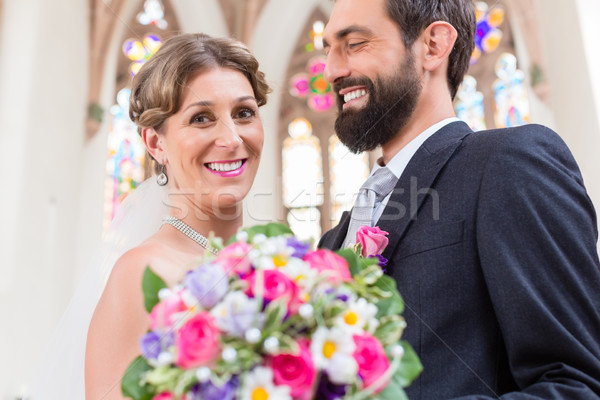 Bridal couple in church with flower bouquet Stock photo © Kzenon