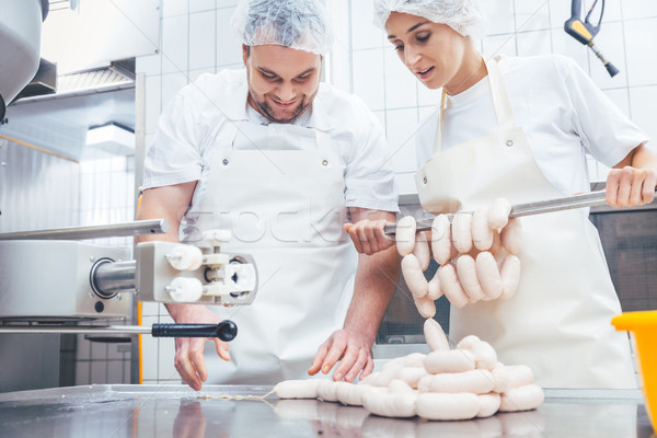 Team of butchers filling sausage in meat industry Stock photo © Kzenon