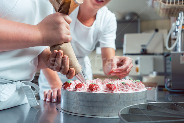 Confectioner or pastry chefs finishing cake with pastry bag Stock photo © Kzenon