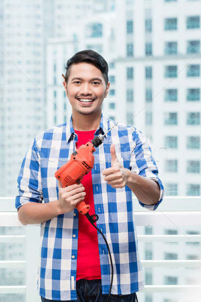 Young indonesian man with power drill Stock photo © Kzenon