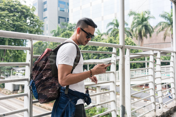 Young tourist using the mobile while walking on a pedestrian bri Stock photo © Kzenon
