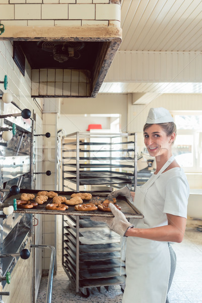 Baker woman getting bakery products out of oven Stock photo © Kzenon