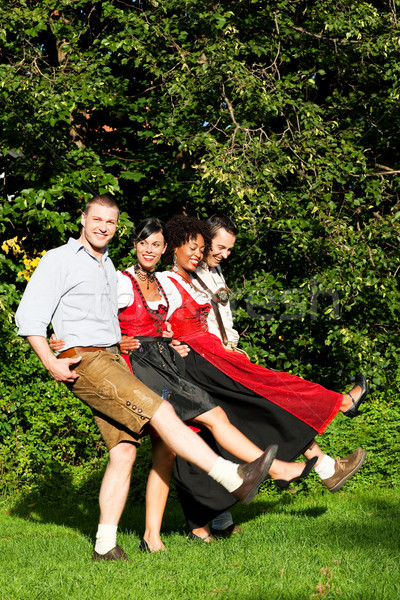 Group of four friends in Bavarian Tracht dancing Stock photo © Kzenon