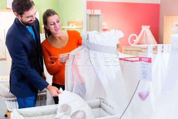 Couple expecting baby buying children bed in store Stock photo © Kzenon