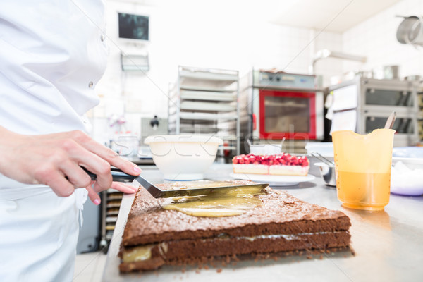 Confectioner woman getting chocolate cake ready with topping Stock photo © Kzenon