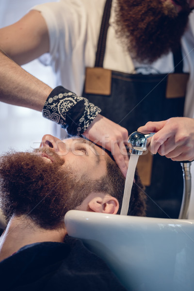 Close-up of the hands of a skilled hairdresser giving a hair wash to customer Stock photo © Kzenon