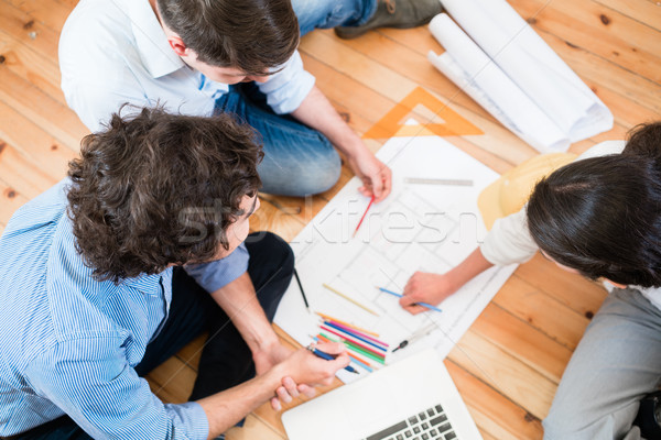 Stock photo: Architects bent over construction plans
