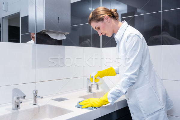 Stock photo: Janitor cleaning sink in public washroom 