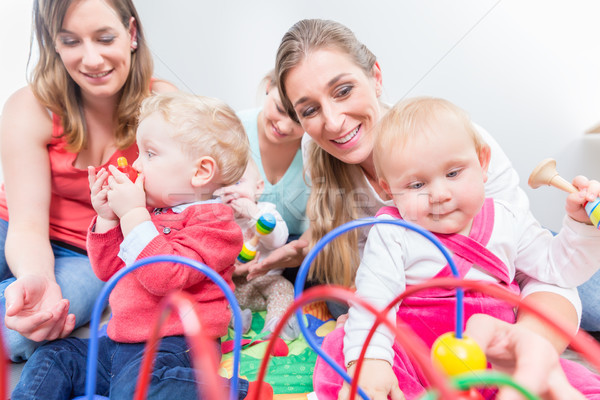 Group of happy young mothers watching their cute and healthy babies play Stock photo © Kzenon