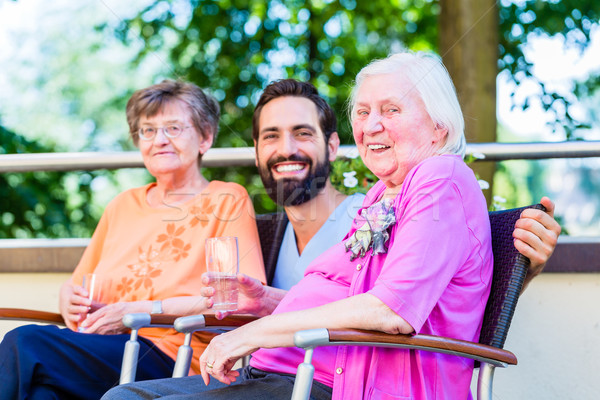 Nurse drinking coffee with seniors on terrace Stock photo © Kzenon