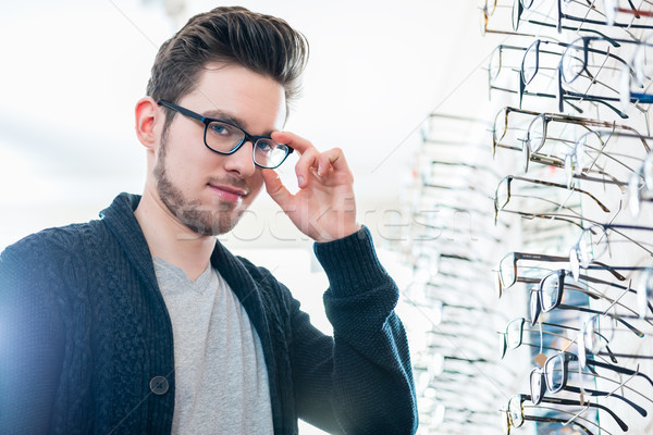 Stock photo: Man in front of shelf with glasses in optician shop