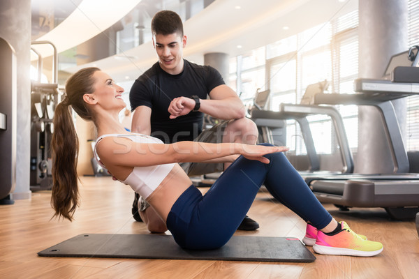 Personal trainer timing young fit woman during isometric exercis Stock photo © Kzenon