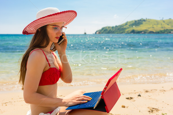 Fashionable young woman talking on mobile phone while using a ta Stock photo © Kzenon