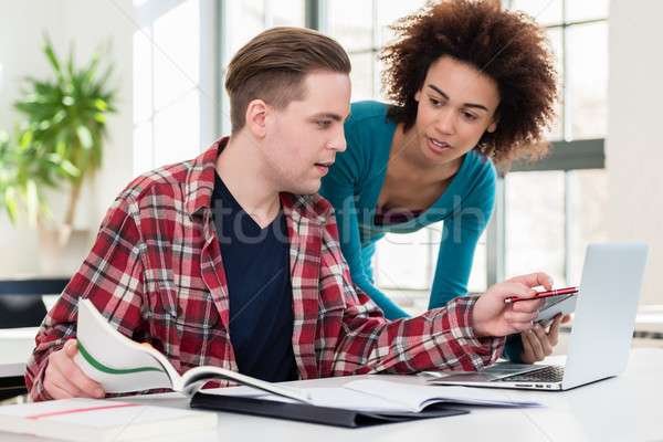 Two young students browsing internet for online useful information Stock photo © Kzenon