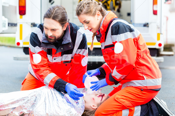 Ambulance doctor giving oxygen to female victim Stock photo © Kzenon