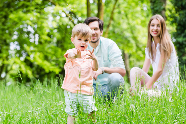 Little boy running over meadow with family in back Stock photo © Kzenon