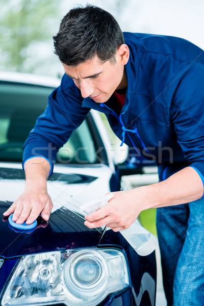 Happy man looking at camera while waxing a blue car Stock photo © Kzenon