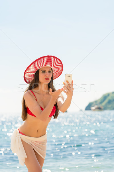 Beautiful woman blowing a kiss while sharing on social media a selfie Stock photo © Kzenon