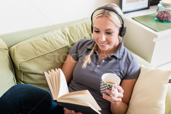 Relaxed young woman reading a book and listening to music Stock photo © Kzenon