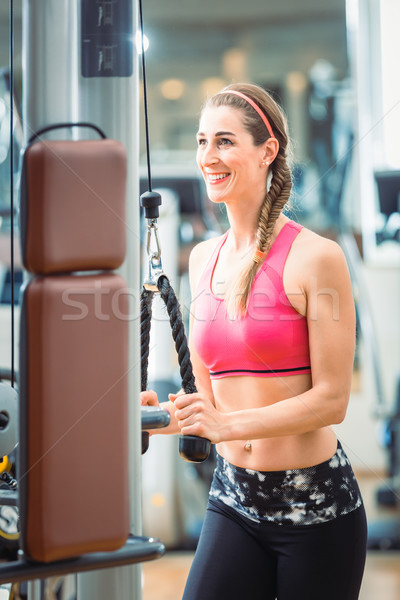 Happy fit woman wearing pink fitness bra while exercising at the gym Stock photo © Kzenon