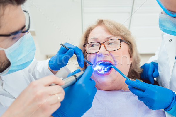 Dentists hardening toot crown with UV light  Stock photo © Kzenon