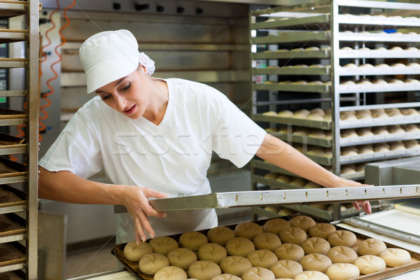 Female baker baking bread rolls Stock photo © Kzenon