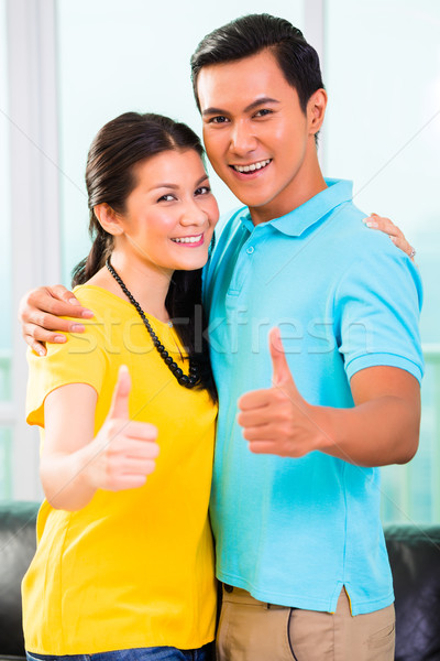 Young Asian couple in apartment with thumbs up Stock photo © Kzenon