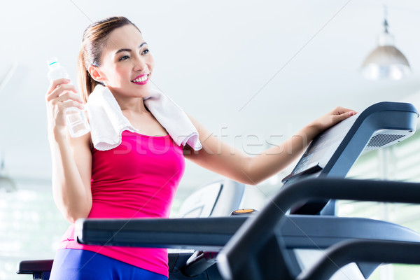Smiling woman on treadmill presenting water bottle Stock photo © Kzenon