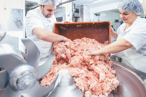 Team of butchers taking minded meat out of grinder Stock photo © Kzenon