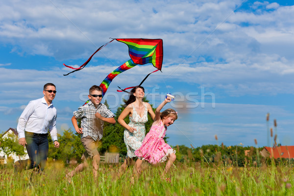 Happy family running on meadow with a kite Stock photo © Kzenon