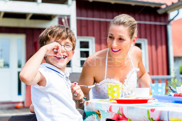 Mother with son eating fruit cake in front of house Stock photo © Kzenon